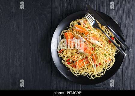 Köstliche Spaghetti mit Krabben Risse in der würzigen Weißweinsauce, bestreut mit gehackter Petersilie und rote Chile über schwarze Platte mit Gabel serviert ein Stockfoto