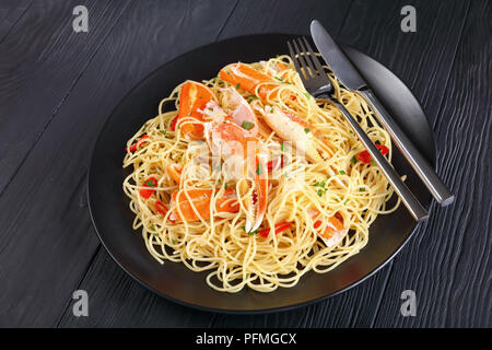 In der Nähe von Spaghetti mit Krabben Risse in der würzigen Weißweinsauce, mit gehackter Petersilie und rote Chile über schwarze Platte mit Gabel serviert sprengte Stockfoto