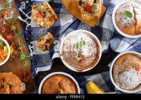 Leckere frisch gebackene selbstgemachte Banane Mutter raisin Muffins bestreut mit Puderzucker in Keramik förmchen und ein Muffin wurde in Stücke gebrochen, vi. Stockfoto