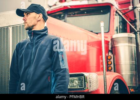 Lkw und Land Transport Industrie Thema. Kaukasische American Semi-LKW-Fahrer vor seiner schweren Lastwagen. Stockfoto