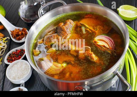 Zutaten für vietnamesische Suppe Pho Bo, mit rohem Fleisch, Knochen Brühe in einen Edelstahl Pfanne, Soja Sprossen, Gewürze, gebackene Zwiebel, Reis, Nudeln, Fisch Sauce, Chili Stockfoto