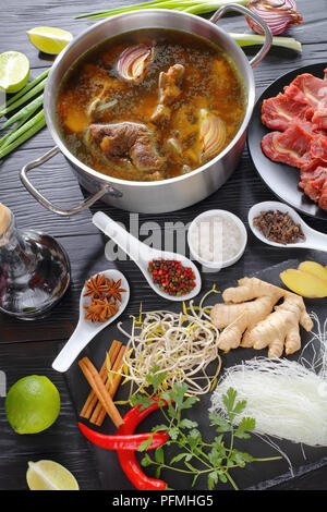 Zutaten für vietnamesische Suppe Pho Bo, mit rohem Fleisch, Knochen Brühe in einen Edelstahl Pfanne, Soja Sprossen, Gewürze, gebackene Zwiebel, Reis, Nudeln, frischen Grüns, Chi Stockfoto
