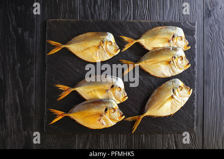 Köstlich kalt geräuchert Mondfische auf schwarzen Stein Fach auf schwarzem Holz- Tabelle, Ansicht von oben Stockfoto