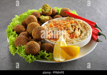 In der Nähe von köstlichen Falafelkugeln auf Platte mit hausgemachten Hummus bestreut mit Paprika und Olivenöl in eine Schüssel geben, Chili Peppers und Salatblätter, au Stockfoto