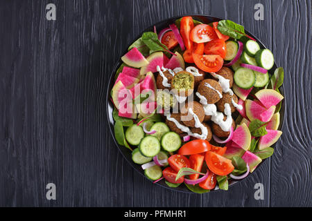 Leckere falafel Kugeln auf Platte mit Gemüse bunter Salat von Wassermelone Rettich, Mangold Blätter, Gurken- und Tomatenscheiben, gesunde Ernährung anhand von quantitativen Simulatio Stockfoto