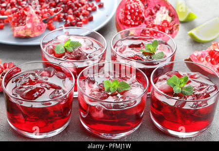 In der Nähe von frisch zubereiteten Granatapfelsaft mit Eiswürfel und frischer Minze im Glas Tassen, Granat Samen und Kalk Schichten in Hintergrund, horizontale Ansicht fr Stockfoto