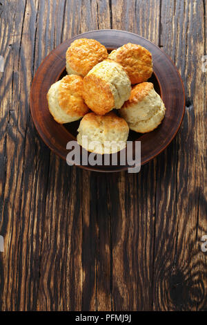 Leckere frisch gebackene hausgemachte englische Scones auf Lehm Platte auf Holztisch, vertikale Ansicht von oben Stockfoto