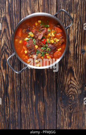 Hot Rindfleisch ungarischen Gulasch oder bograch Suppe mit Paprika, kleine Eier Nudeln, Gemüse und Gewürze in einem Topf auf Holztisch, klassisches Rezept, Ansicht von ab Stockfoto