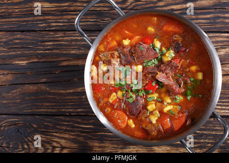 Hot Rindfleisch ungarischen Gulasch oder bograch Suppe mit Paprika, kleine Eier Nudeln, Gemüse und Gewürze in einem Topf auf Holztisch, klassisches Rezept, Ansicht von ab Stockfoto