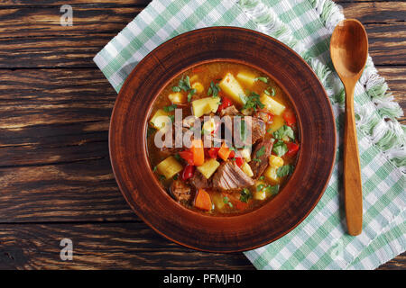 Hot Rindfleisch ungarischen Gulasch oder bograch Suppe serviert in einem Ton Schüssel mit Löffel aus Holz auf Serviette auf Holztisch, authentische Rezept, von oben, Ansicht schließen Stockfoto