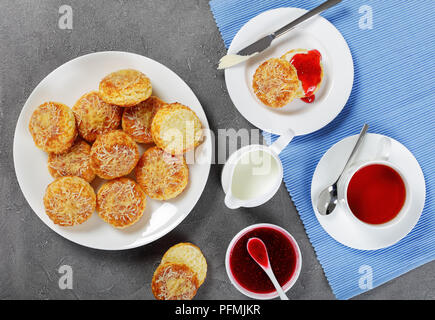 Englisches Frühstück - Tasse Tee mit Krug Milch serviert und frisch gebackene leckere englische Scones mit Marmelade und Butter, Ansicht von oben Stockfoto