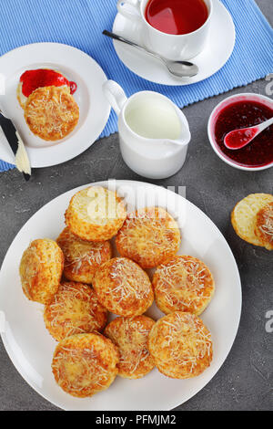 Englisches Frühstück - frisch gebackene leckere englische Scones mit Marmelade und Butter, Tasse Tee und kanne Milch, vertikale Ansicht von oben Stockfoto