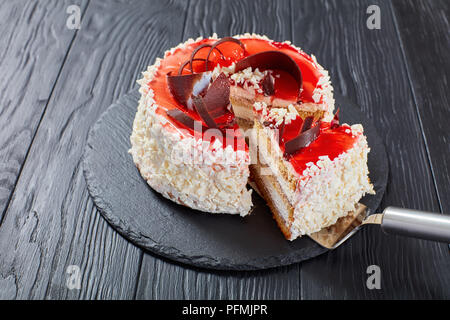 Köstliche Kuchen, überlagert mit Frischkäse Mousse mit weißer Schokolade Flocken, roten Beeren Marmelade und Schokolade Chips auf schwarzem Schiefer Platte eingerichtet Stockfoto