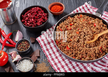 Zutaten zum Kochen Chili con Carne - gebratene Hackfleisch auf Skillet, Paprika, Chili, gehackten Tomaten, rote Bohnen, Zwiebeln und Stücke von Chocola Stockfoto