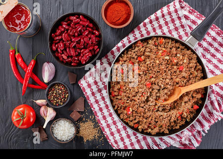 Zutaten zum Kochen Chili con Carne - gebratene Hackfleisch auf Skillet, Paprika, gehackten Tomaten, rote Bohnen, Zwiebeln und Stücke Schokolade, aut Stockfoto