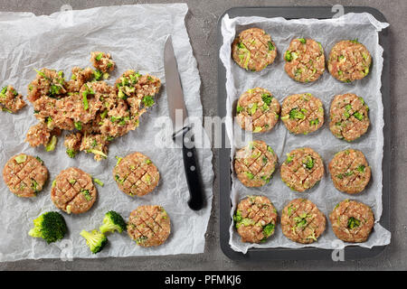 Fleisch Brokkoli Pastetchen aus raw forcemeat, Brokkoli gebildet, geriebener Käse, Panko Paniermehl, Eier, Gewürze auf Blech und auf Papier auf Holz Tabl Stockfoto