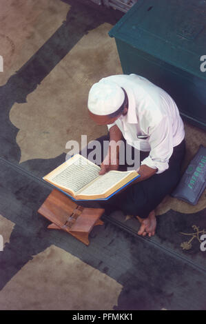 Singapore, Singapore City, Kampong Glam, mann lesen den Koran auf dem Boden einer Moschee, hohe Betrachtungswinkel sitzt Stockfoto