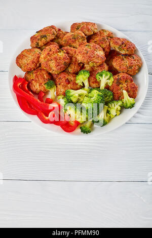 Saftiges Huhn Brokkoli Frikadellen gefüllt mit geriebenem Käse, auf weißem Schild auf Holztisch, gesunde niedrige Kalorien Rezept, vertikale Ansicht von oben Stockfoto
