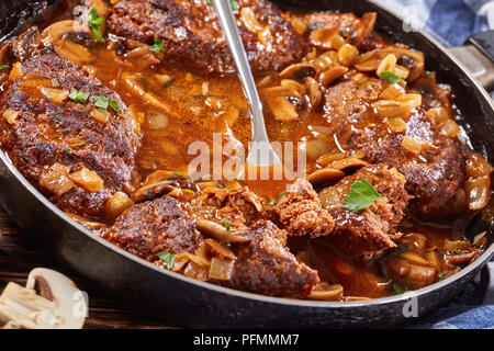 In der Nähe von Salisbury heißen herzhaften saftige Rindersteaks Ganze und man war in Stücken mit köstlichen Pilz Soße Zwiebel in einer Pfanne mit der Gabel gebrochen, Anzeigen Stockfoto