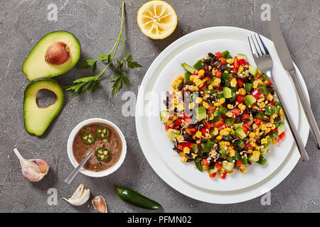 In der Nähe des mexikanischen Salat mit Avocado, Bohnen, Mais, Buchweizen Sprossen, gewürfelt Pfeffer auf Platten mit Zutaten und Vinaigrette dressing Co Stockfoto