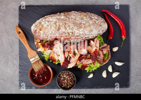 Nahaufnahme der leckere saftige riesen BBQ Rib Sandwich von Roggenbrot Brot mit frischen grünen Salat, zerkleinertem Schweinefleisch, und leckere hausgemachte Barbecue Sauce, Stockfoto