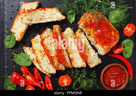 Lecker fisch Terrine in Scheiben geschnitten mit Pfeffer, frische Grün und Tomatensauce auf schwarzem Schiefer Schneidbrett auf einem dunklen Holztisch, Ansicht von oben Stockfoto