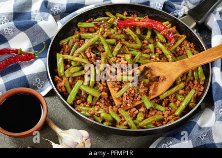 Szechuan rühren Gebratene grüne Bohnen mit Schweinefleisch in einer Pfanne mit Holzspachtel, Ansicht von oben, in der Nähe Stockfoto