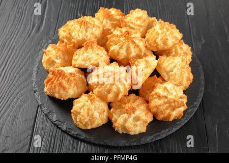 Leckere Kokosnuss Makronen Cookies auf einer Platte auf einem schwarzen Holz- Tabelle, Ansicht von oben, close-up Stockfoto