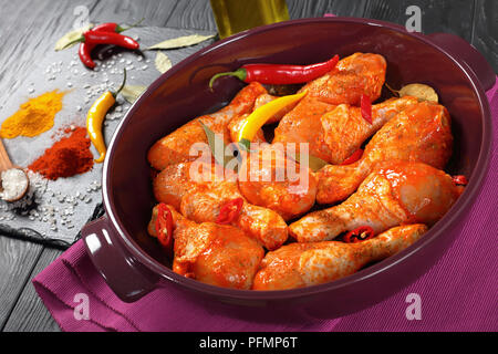 Roh marinierte Chicken Drumsticks mit Gewürz bestreut, Chili, Pfeffer, Lorbeer bereit, in einem Gericht zu kochen, Zutaten auf einen Stein auf eine Stockfoto