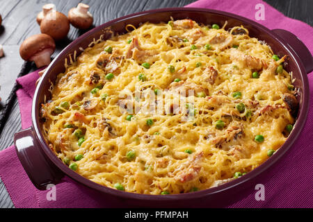 Tetrazzini - Spaghetti, Putenfleisch, geriebener Käse, grüne Erbsen, Champignons Auflauf in einer Auflaufform mit Zutaten im Hintergrund, amerikanische Rezept, Stockfoto