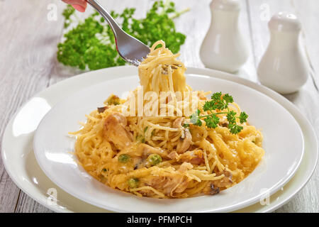 Weibliche hand eine Gabel mit Teil der Tetrazzini, klassische amerikanische Auflauf von Einfügen, Geflügel Fleisch, Pilzen und Käse, Ansicht von oben, Clo Stockfoto