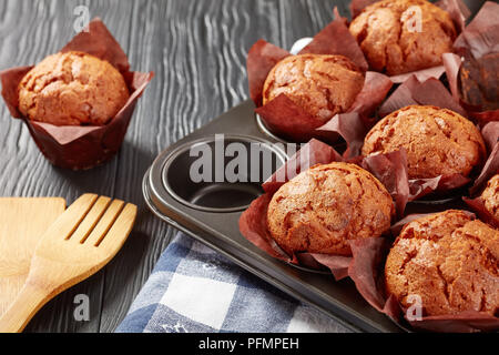 Frisch gebackene Muffins auf schwarzen Holztisch und in einen Stahl Backblech mit Küchentuch, Ansicht von oben, close-up Stockfoto