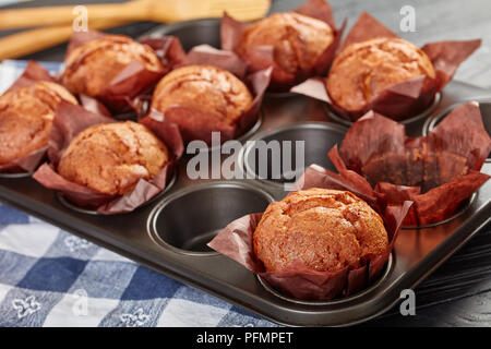 Frisch gebackene Muffins in eine Backform mit Küchenpapier auf einem Holztisch, Ansicht von oben, close-up Stockfoto
