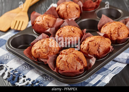 Frisch gebackene hausgemachte Muffins in einem Backblech mit Küchenpapier auf einem Holztisch, Ansicht von oben, close-up Stockfoto