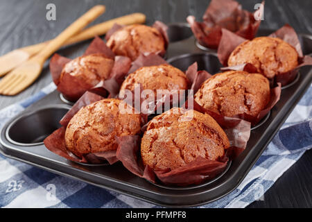 Köstliche Muffins in einem Stahl Backblech mit Küchentuch auf schwarzem Holz- Tabelle, Ansicht von oben, close-up Stockfoto