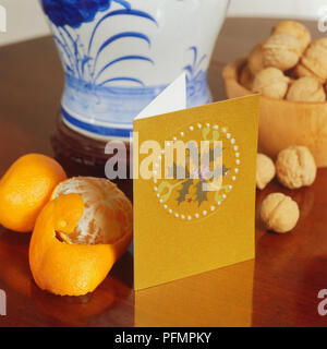 Weihnachtskarte auf hölzernen Tisch neben Mandarinen und Walnüssen. Stockfoto