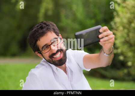 Glückliche junge Mann ein selfie im Park Stockfoto