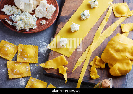 Ungekocht Ravioli, ei Pastateig, ricotta Füllung gemischt mit fein gehacktem grünen auf einer konkreten Küche Tabelle, Ansicht von oben, close-up Stockfoto