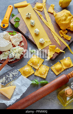 Die Herstellung von köstlichen Ravioli mit Ricotta Füllung mit fein gehackte Minze und Basilikum auf einer konkreten Küchentisch mit Zutaten gemischt, Stockfoto