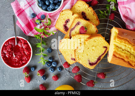 Frisch gebackene Scheiben geschnittenen Zitrone Pound Cake mit Beeren marmelade Füllung auch als Torte de voyage Kuchen auf dem konkreten Hintergrund mit Inhaltsstoffe bekannt, französisch Stockfoto
