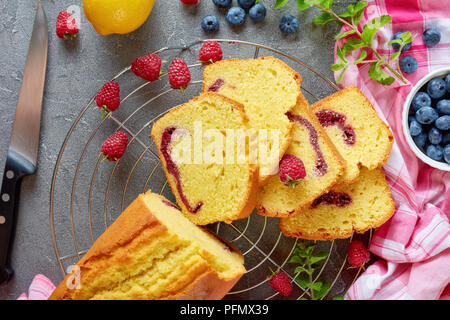 Frisch gebackene Scheiben geschnittenen Zitrone Pound Cake mit Beeren marmelade Füllung auch als Torte de voyage Kuchen auf einen konkreten Hintergrund mit Inhaltsstoffe bekannt, französisch c Stockfoto