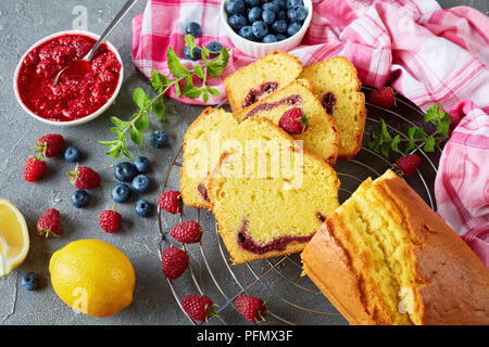 In der Nähe von frisch gebackenen aufgeschnittene Zitrone Pound Cake mit Beeren marmelade Füllung auch als Torte de voyage Kuchen auf einer konkreten Tabelle mit Inhaltsstoffe bekannt, f Stockfoto