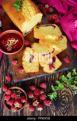 Zitrone Pound Cake mit himbeermarmelade füllen auch als Torte de voyage Kuchen auf einem alten Holztisch bekannt, dunklen rustikalen Stil, die französische Küche, vertikale vi. Stockfoto