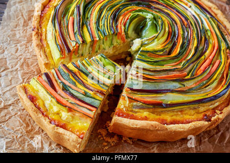 Pflanzliche Spirale Tarte mit Zucchini, Aubergine, Möhren Schichten mit ricotta Käse und Ei Füllung in Scheiben geschnitten auf einem Papier, Ansicht von oben Stockfoto