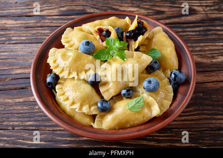 Heidelbeerknödel, Pierogi, vareniki in einem Ton Schüssel auf eine alte Küche Tabelle, Seite, Ansicht von oben, close-up Stockfoto