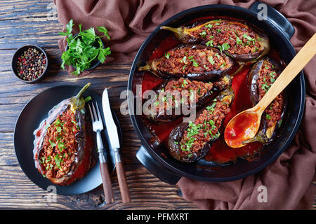 Karniyarik Gefüllte Auberginen Auberginen mit Hackfleisch und Gemüse überbacken mit Tomatensauce auf einem Teller mit Messer und Gabel serviert, türkische Cuis Stockfoto