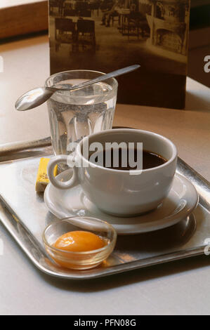 Kaisermelange, Kaffee mit Eigelb, Zucker und Cognac, serviert mit einem Glas Wasser auf Serviertablett, eine Kaffeespezialität aus Österreich Stockfoto