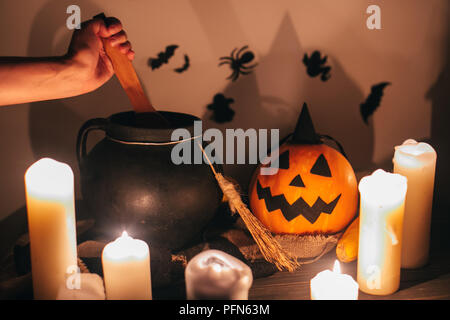 Happy Halloween. Hexe hand kochen Trank für Zauber, mit jack o lantern Kürbis mit Kerzen, Schüssel, Besen und Fledermäuse, Geister im Hintergrund in dunklen Spoo Stockfoto