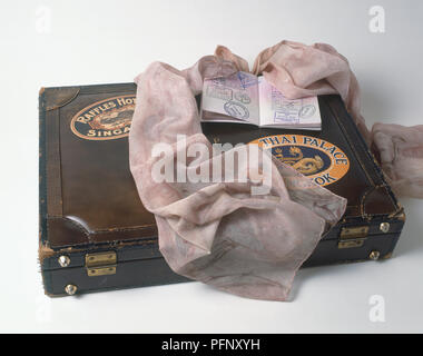 Ein rosa Schal und einem offenen Pass auf einem alten Leder Koffer. Stockfoto