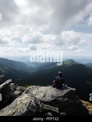 Eine einsame Touristen sitzen auf dem Rand der Klippe Stockfoto